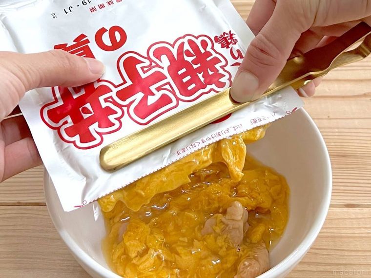 レトルトパウチの中身をトングでしぼり出している