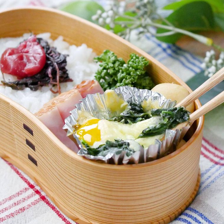 敷物の上に乗った曲げわっぱのお弁当に冷凍ほうれん草のココットが入っている