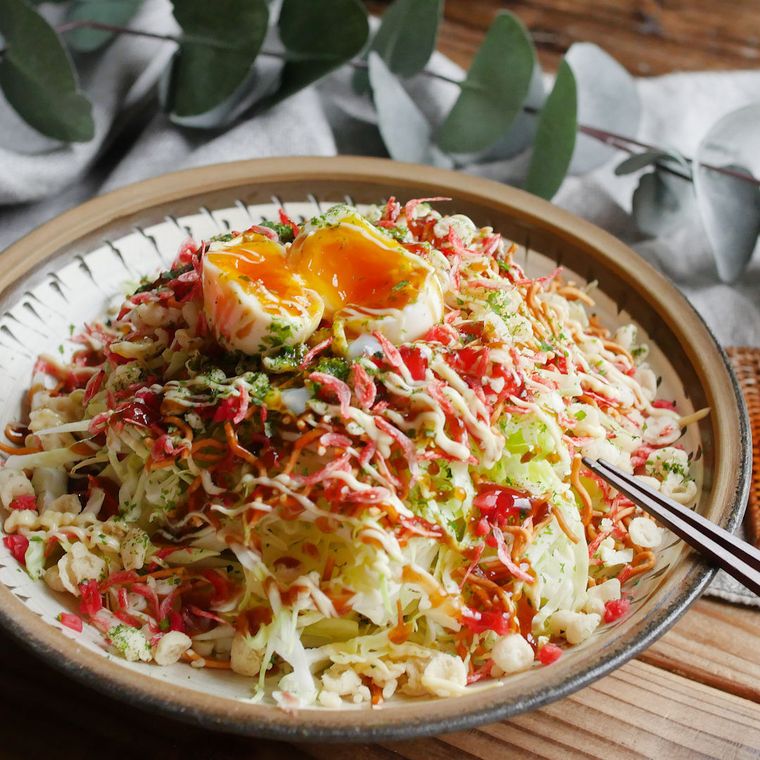 お好み焼き風野菜サラダが茶色の皿に盛り付けられているところ