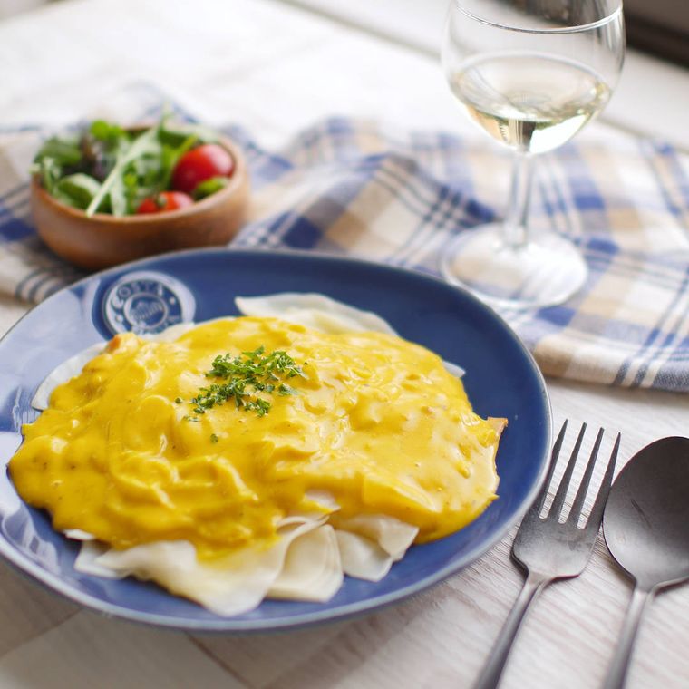 青い皿に盛り付けたかぼちゃソースのラビオリ風