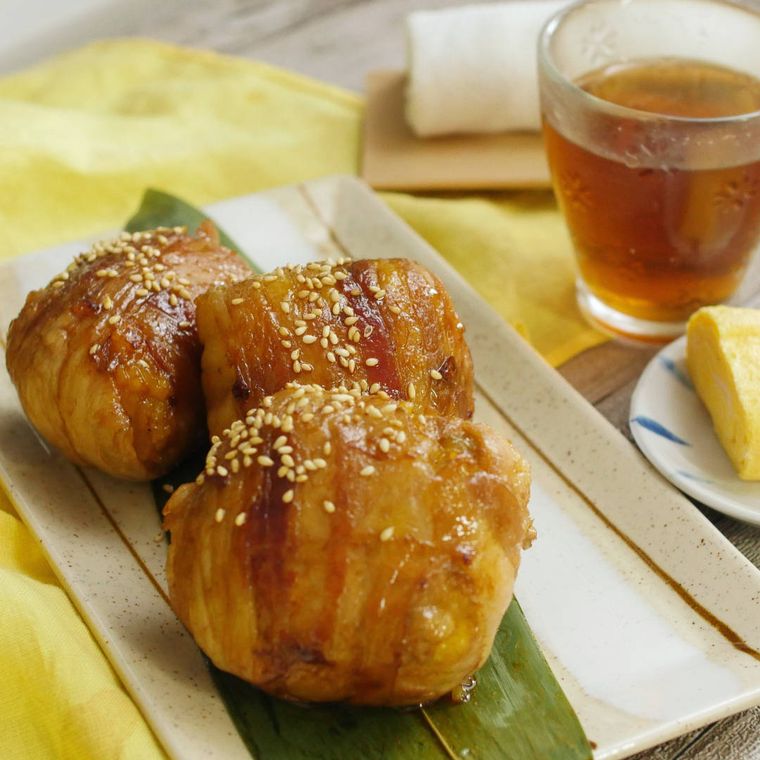 白い皿に盛り付けたかぼちゃごはんの肉巻きおにぎり