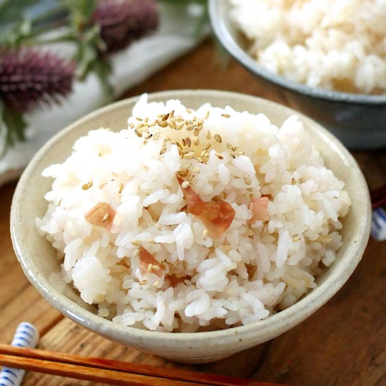 茶碗に盛られた梅干しの炊き込みごはんと、振りかけられた白いりごま