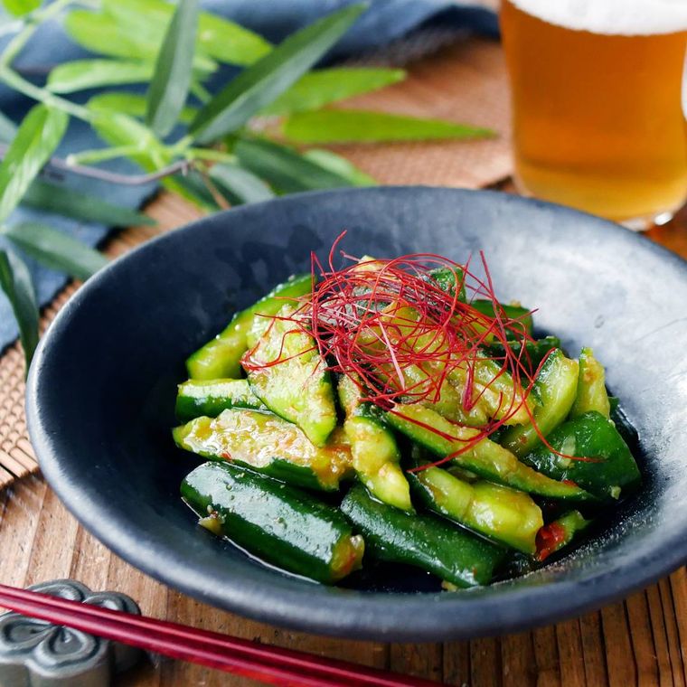 黒色の丸皿に盛られた麻辣きゅうり、ビール