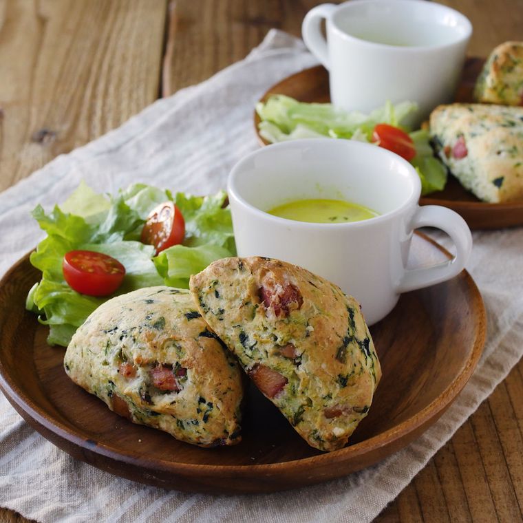 オリーブオイルを使うベーコンとほうれん草のスコーンが木の皿に盛り付けられているところ