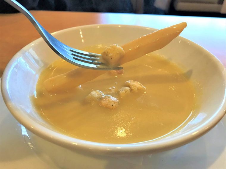 とうもろこしのポタージュに、フォークで刺したフライドポテトをつけている