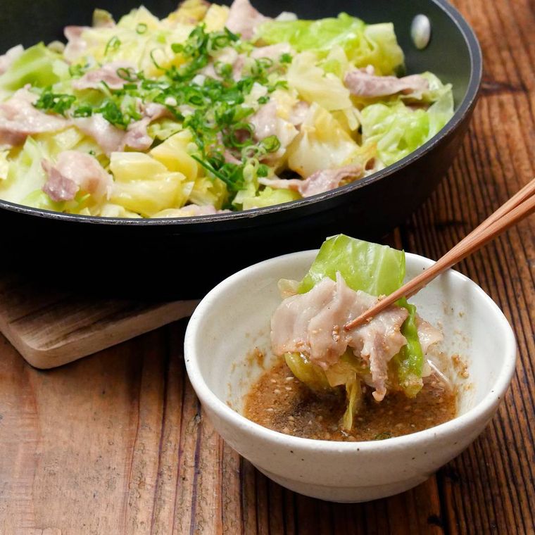 黒い皿に盛り付けた豚肉とキャベツのフライパン蒸し
