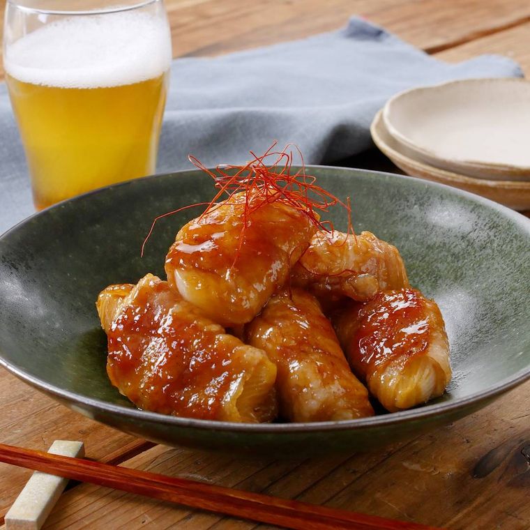 黒色の丸皿に盛られた新玉ねぎの豚バラ肉巻き