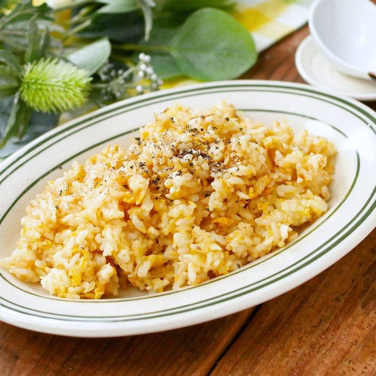 緑色の縁取りのある白色の皿に盛られた玉ねぎと卵のチャーハン