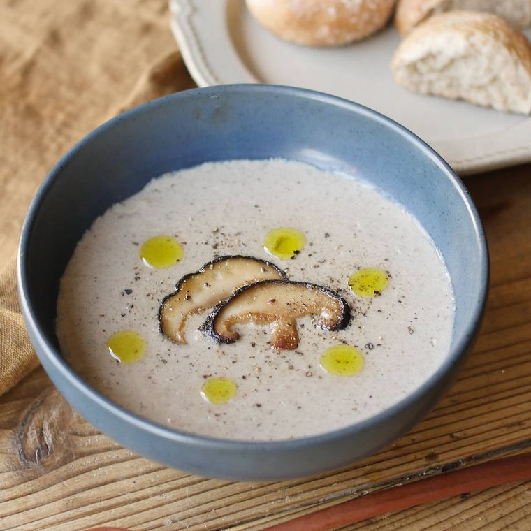 青い皿に入ったベーコンとしいたけのポタージュ