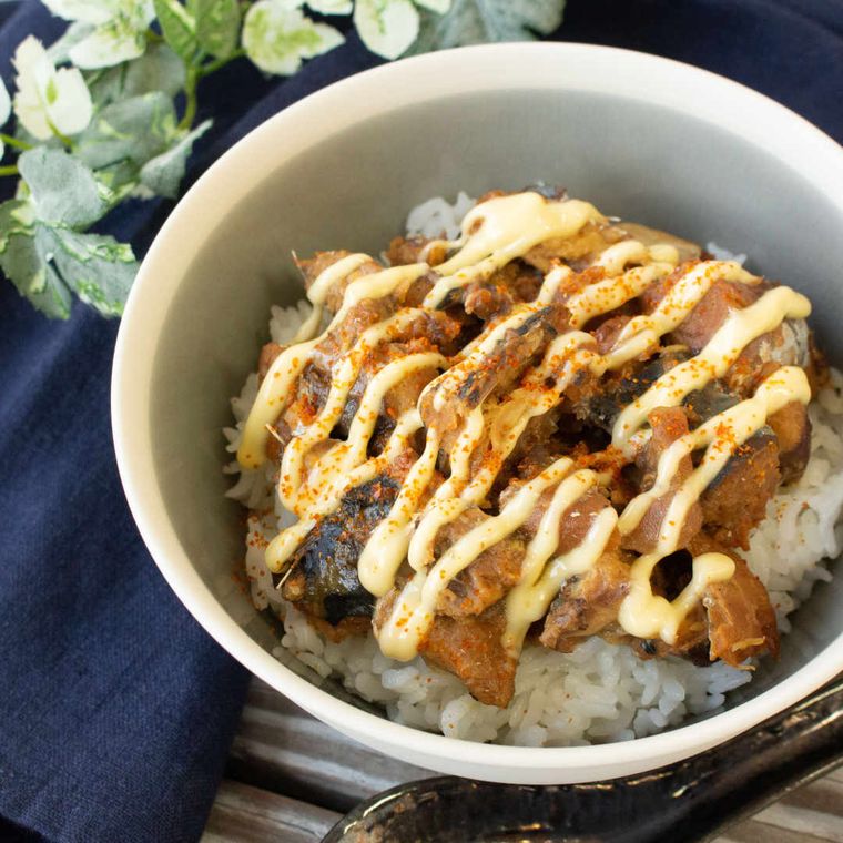 マヨネーズがかかっているさば味噌煮缶と梅干しの丼