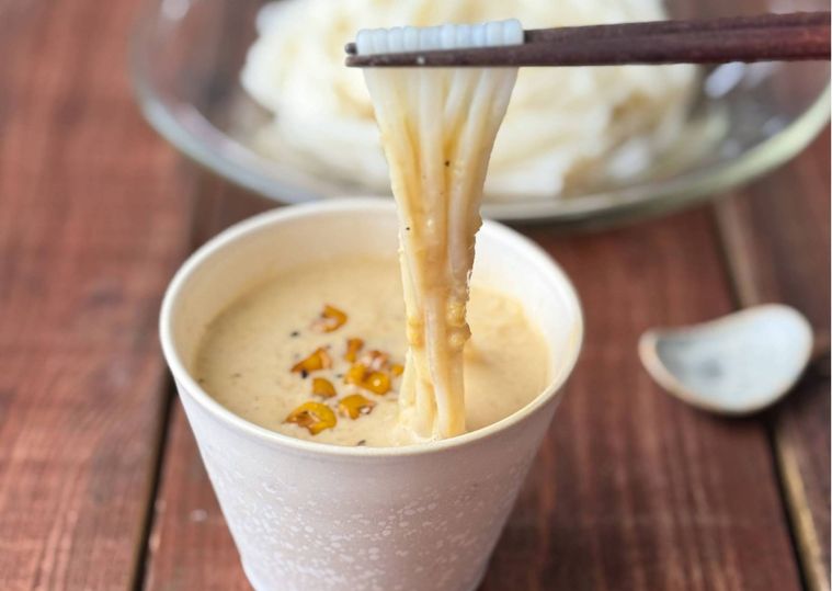 蕎麦ちょこに入ったとうもろこしのつゆにそうめんをつけている