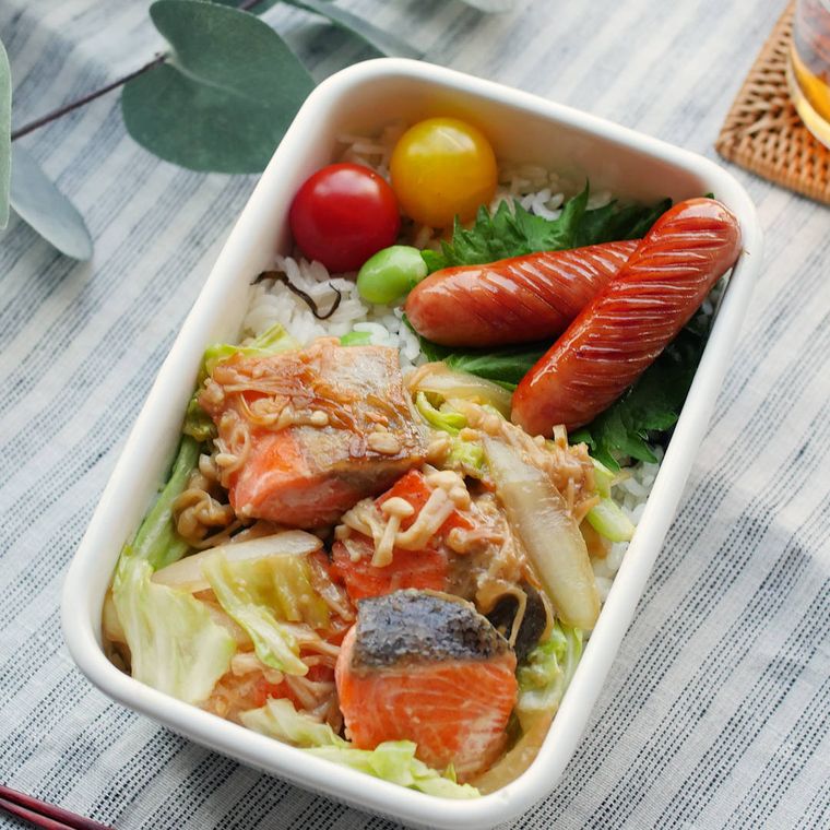 白いホーロー容器に入った、鮭とキャベツのちゃんちゃん焼き、枝豆と塩こんぶのごはん、ウインナーソーセージ、ミニトマトの弁当