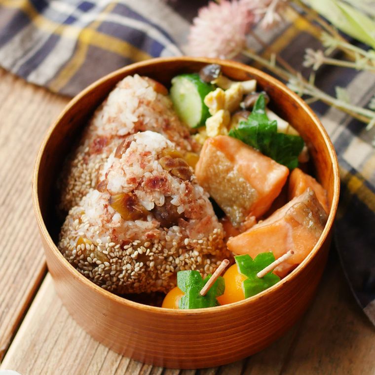 弁当箱に入った栗ごはんのおにぎりと鮭のバターポン酢ソテー、きゅうりとしめじの卵炒め、ミニトマト