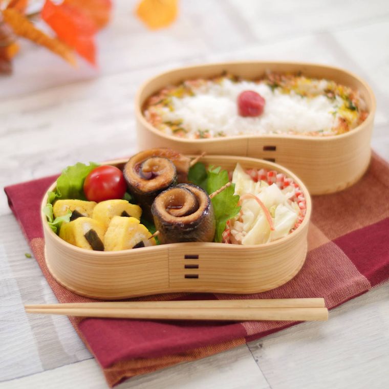 曲げわっぱの弁当箱に入った、さんまの蒲焼と卵焼き、キャベツとカニカマの和え物、ミニトマト、大葉、梅干しののったごはん