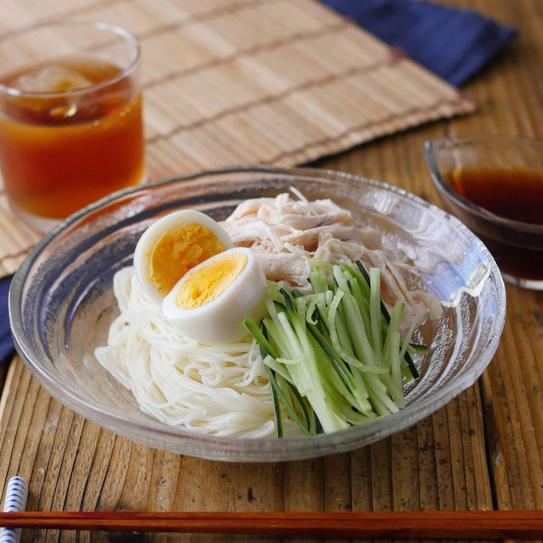 透明な器に盛り付けられたそうめんにゆで卵やきゅうりがトッピングされている