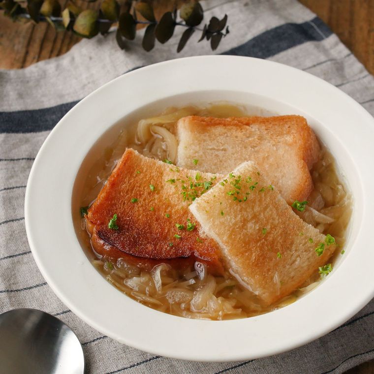 トーストを浮かべたオニオンスープが、白い器に盛られている