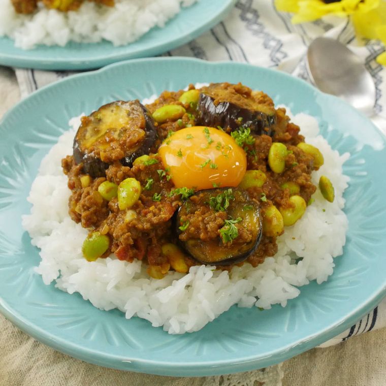 なすと枝豆のキーマカレーが青い皿に盛り付けられているところ