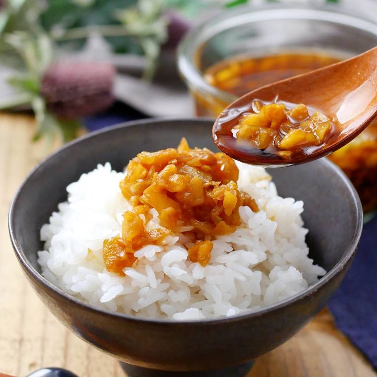 黒い茶碗に盛り付けたごはんに無限にんにくをのせている様子