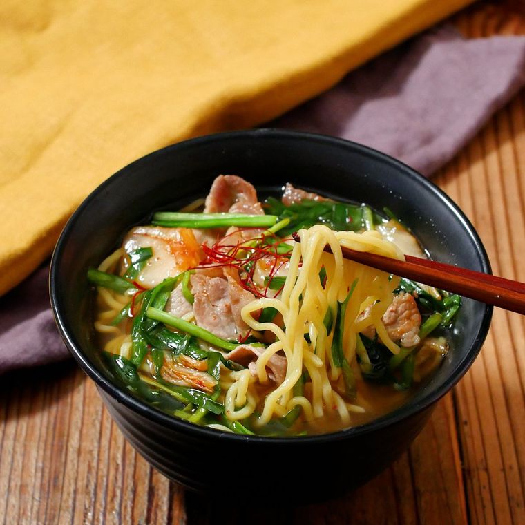 黒い丼に入った豚バラ肉、キムチのスタミナニラそば