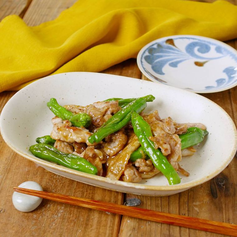 白い器に盛りつけられたししとうがらしと豚こま肉の甘辛炒め