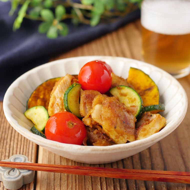 夏野菜と鶏肉のスパイシーソテーが白い和風の深皿に盛り付けられているところ