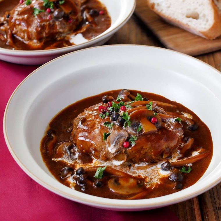 デミグラス煮込みハンバーグが白い円形の器に盛り付けられているところ