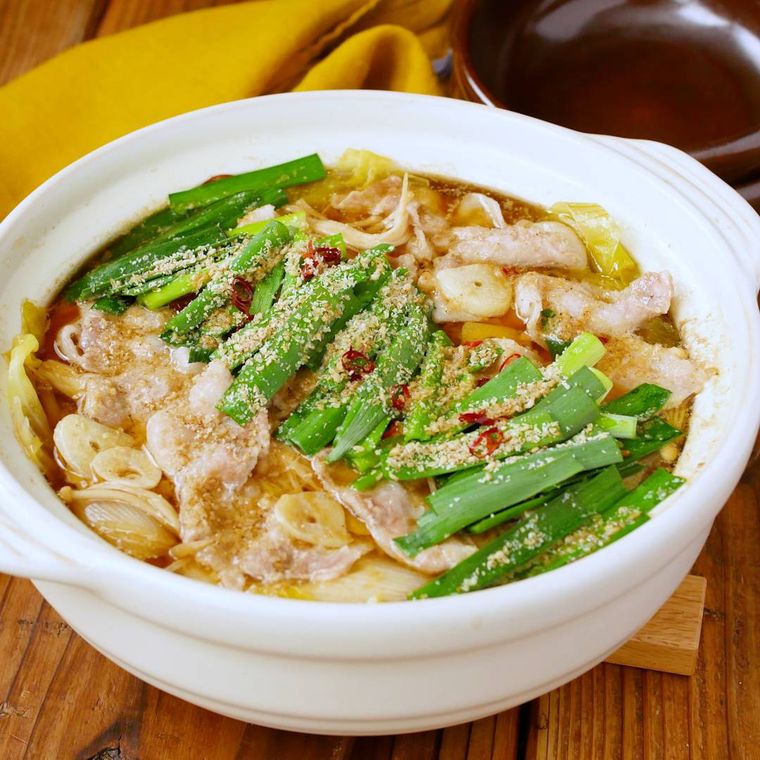 白い土鍋に入った豚バラ肉のにんにく鍋