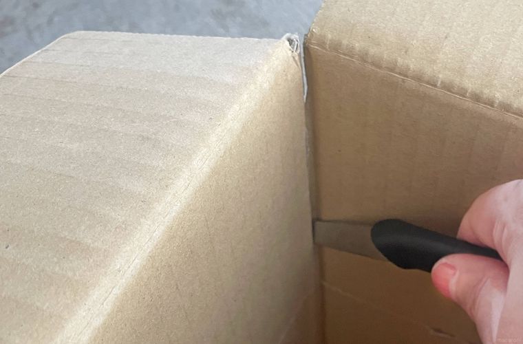 段ボールの隅をカッターで切っていく様子