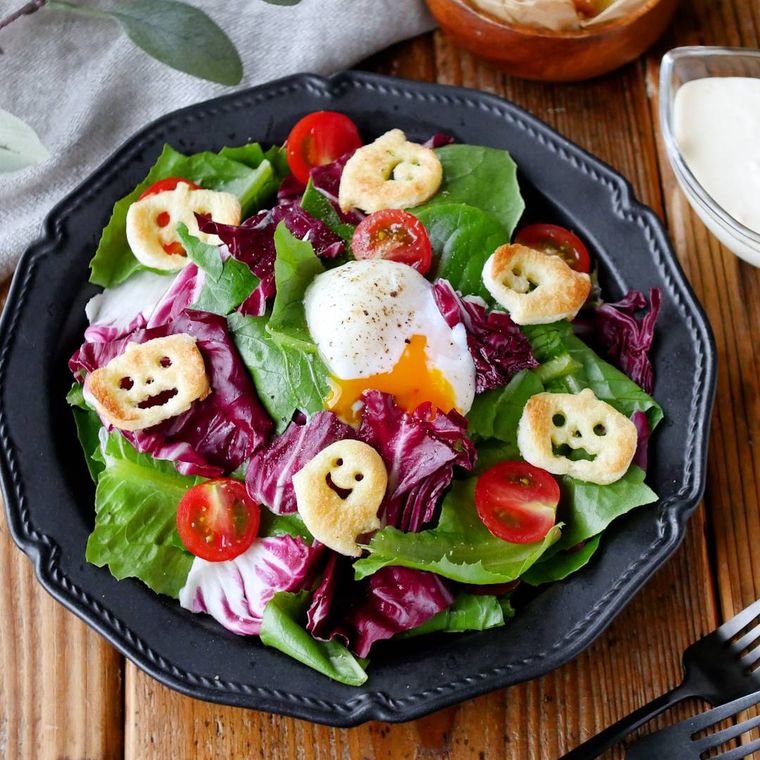 黒い丸皿に盛り付けられたハロウィン仕様のシーザーサラダ