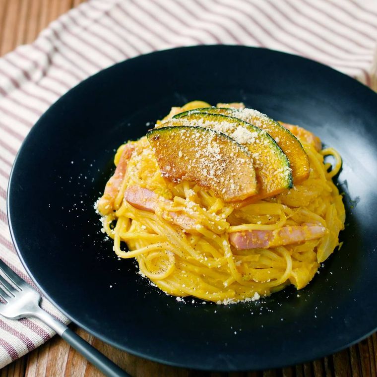 黒い丸皿に盛り付けられたかぼちゃのみそクリームパスタ