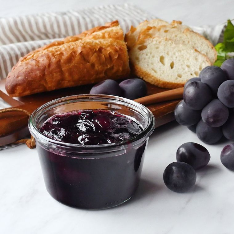 ガラスの器にぶどうジャムが入っておりバゲットが添えられている