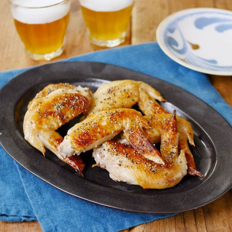 黒い皿に盛り付けた手羽先のにんにく旨塩焼き