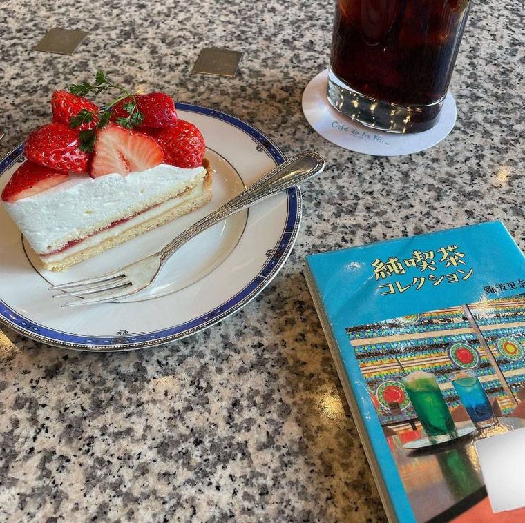 テーブルに置かれたケーキセットのケーキとアイスコーヒー、本