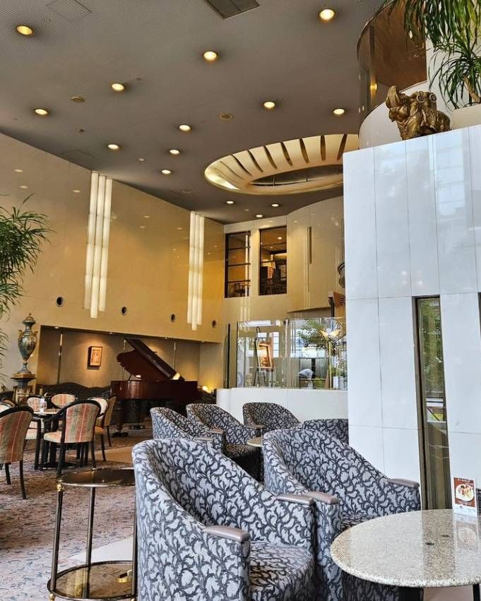 奥にグランドビアノが置かれテーブル席やソファ席が並ぶカフェ・ド・ラ・ペの店内