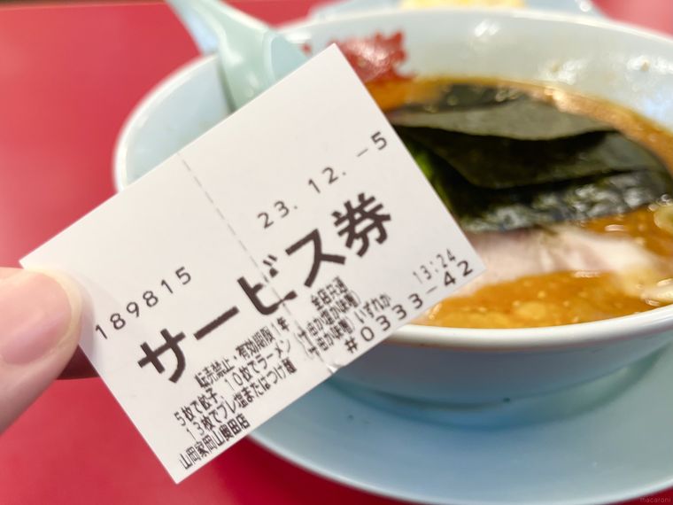 ラーメンを背景にサービス券を持っている様子