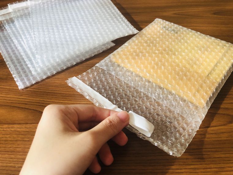 CDを入れたプチプチ袋のテープを剥がしている
