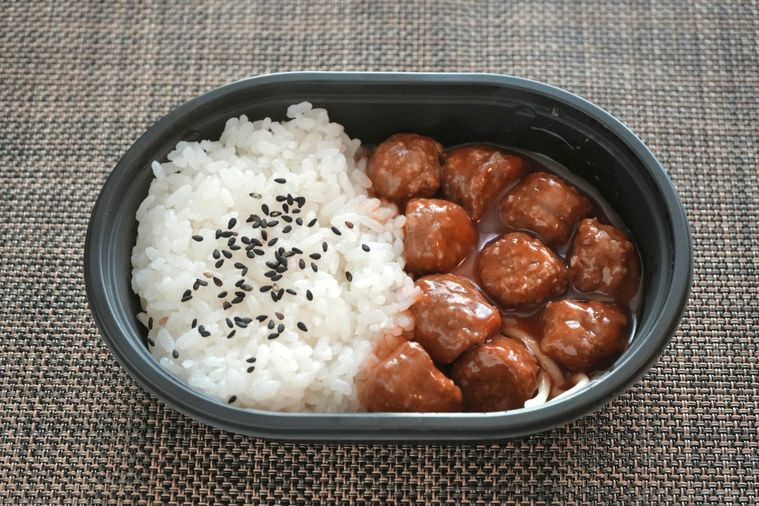 茶色いランチョンマットとミートボールとパスタとごまごはんのコンビニ弁当