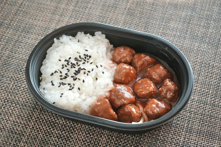 茶色いランチョンマットとミートボールとパスタとごまごはんのコンビニ弁当