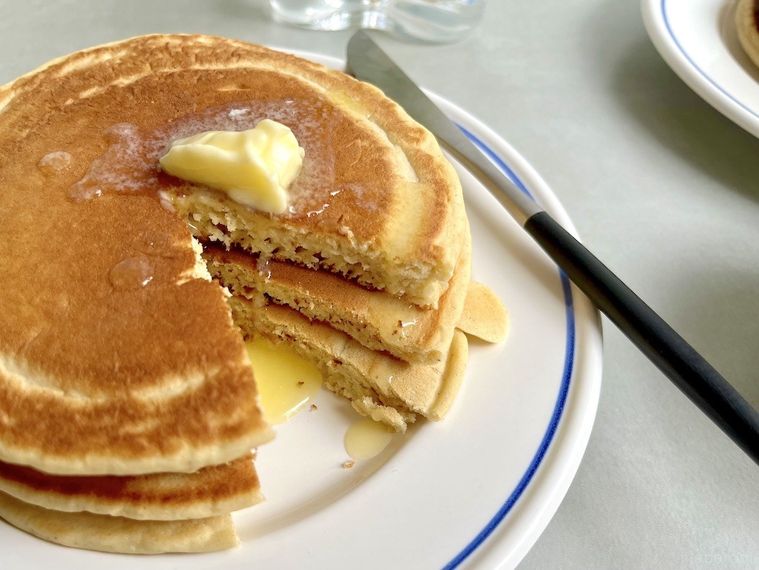 3枚重ねてカットしたパンケーキの断面に、上にのせたバターが溶けて流れているところ