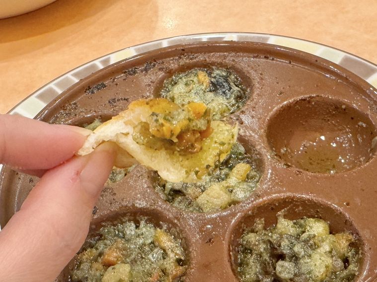 プチフォッカにエスカルゴのオーブン焼きのソースをのせている様子