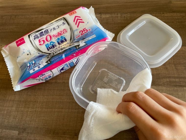 テーブルに置いた保存容器を除菌シートで拭いている様子