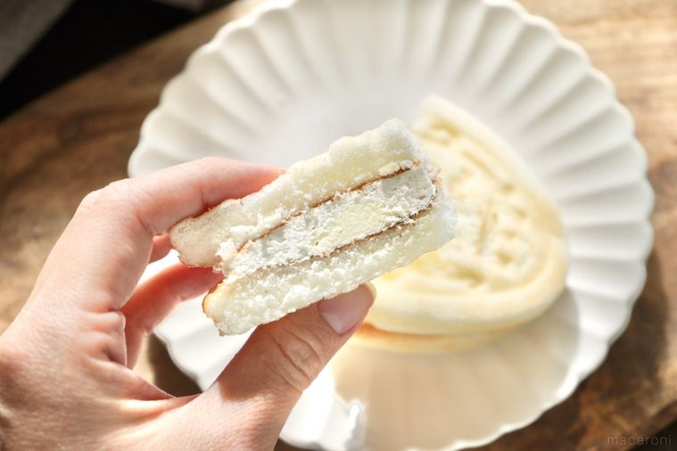 木のカッティングボードと白い皿にのった白いワッフルの断面と手