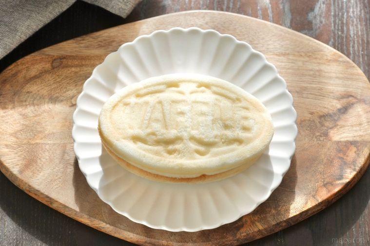 木のカッティングボードと白い皿にのった白いワッフルとグレーの布