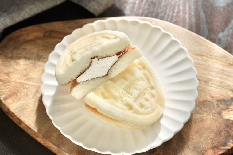 木のカッティングボードと白い皿にのった白いワッフル