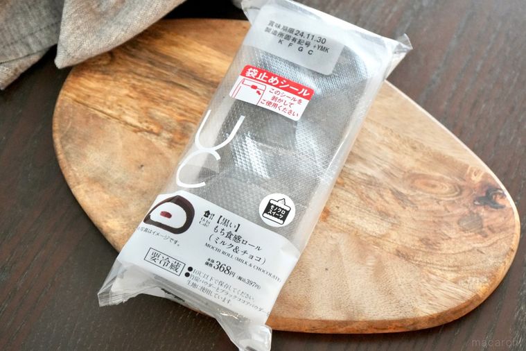 木のカッティングボードにのった黒いもち食感ロールとグレーの布