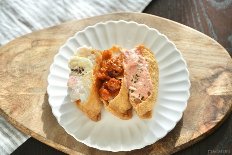 木のカッティングボードと白い皿にのった3種類の具材の韓国風いなり寿司のユブチョバプ