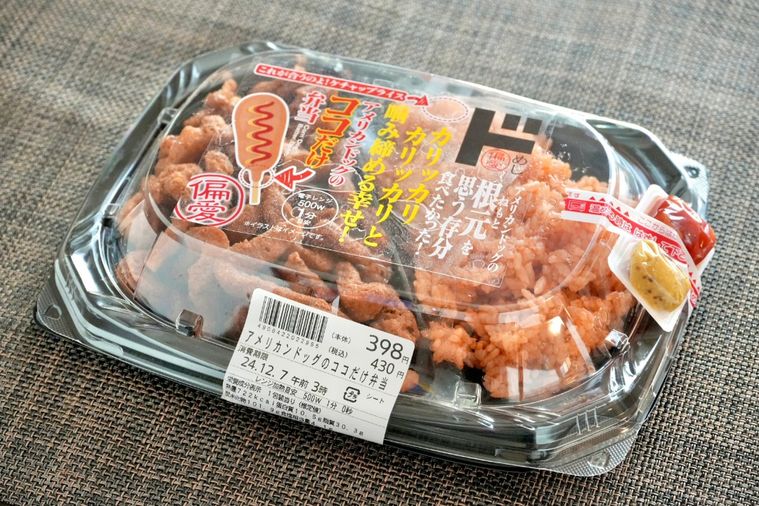 茶色いクロスにのった黒い容器のアメリカンドッグのココだけ弁当