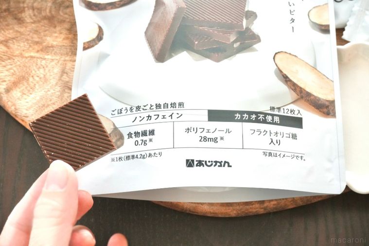 木のカッティングボードにのったパッケージと手に持ったごぼう由来のチョコレート