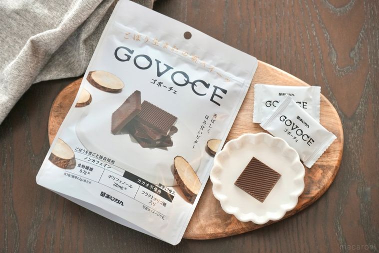木のカッティングボードと白い小皿にのったごぼう由来のチョコレートとグレーの布
