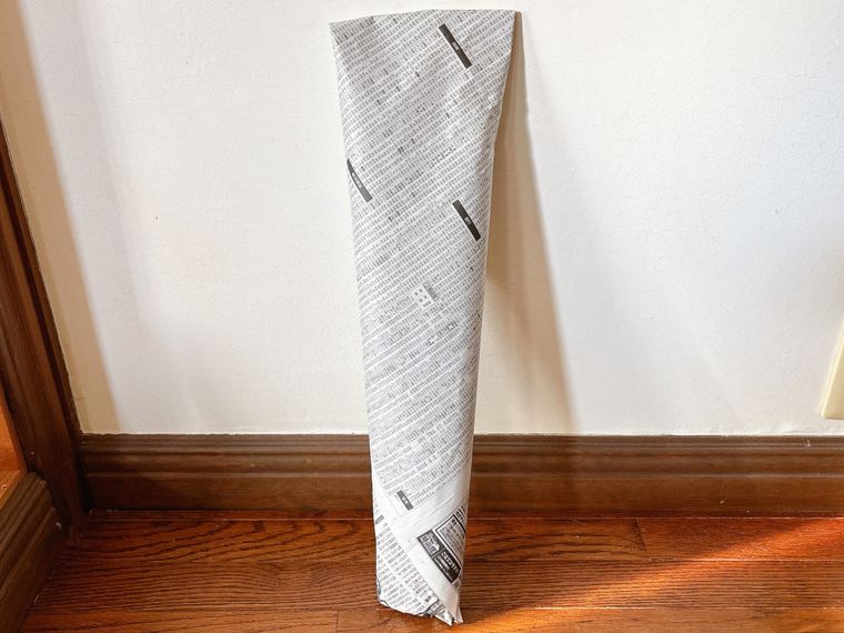 長ねぎを丸ごと1本新聞紙で包んだものを立てた様子